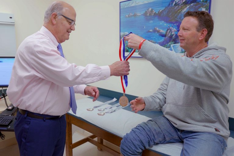 Jeff Morse shows UConn Health orthopedic surgeon Robert Arciero his pickleball medal