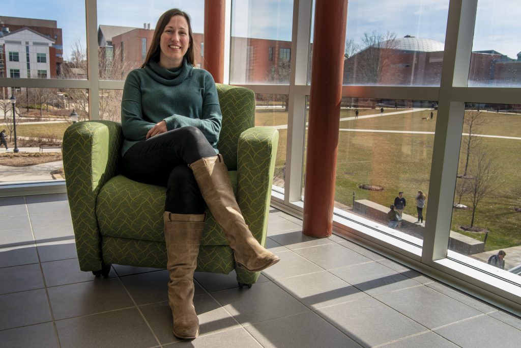 Photo of Brandi Simonsen seated on a green chair by a window at the Neag School of Education.