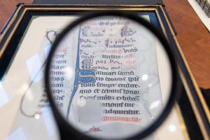A section written on a leaf from the Beauvais Missal can be seen through a magnifying glass in the Dodd Center for Human Rights