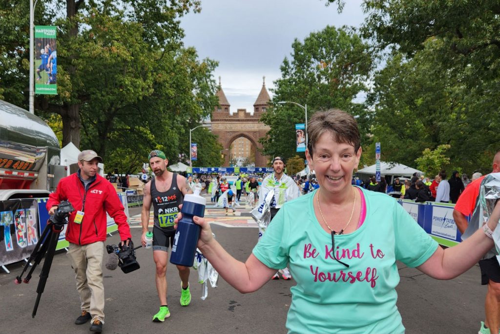 Sherri Beck at Hartford Half Marathon with her shirt imprinted with the phrase "Be kind to yourself."