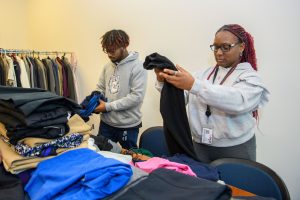Nicholas Roman '27 (ENG) and Tiarra Shaw '27 (CLAS) fold items at the Clothing for All closet at the Stamford campus