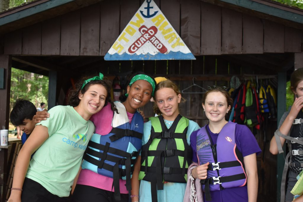Four people smile at the camera, wearing life jackets.