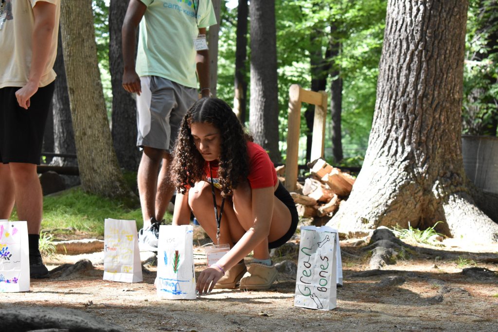 A student places a hand-decorated paper bag luminary on the ground next to others.