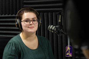 Kelsey Hammerman ’17 (CLAS) sits in front of a microphone in a recording studio.