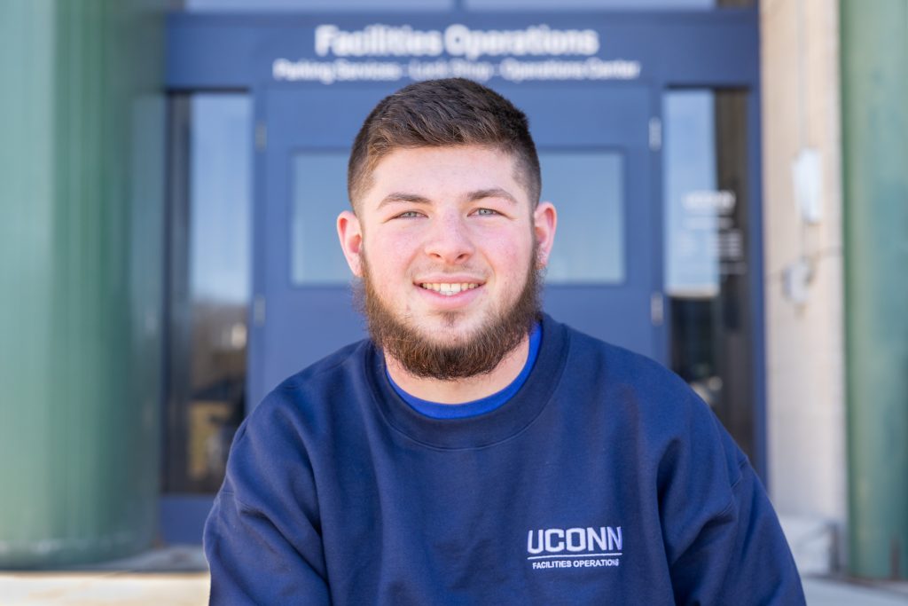 UConn Facilities Operations employee Jared Gauthier poses for a photo outside the Facilities Operations building
