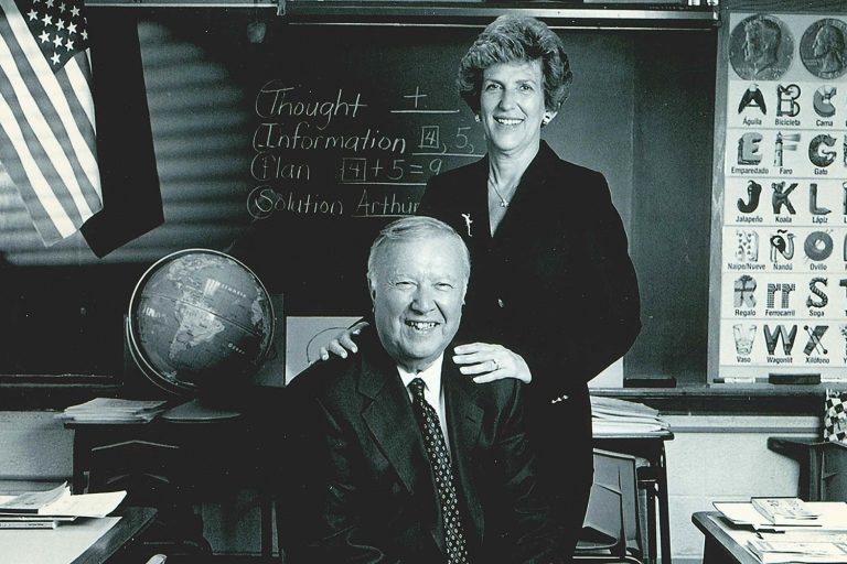 Ray and Carole Neag pose in a classroom.
