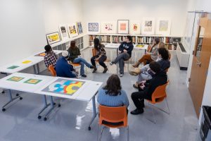 Students in professor Enrique Figueredo's Printmaking Workshop class (ART 3530) observe and discuss some of the artwork put on display by Assistant Curator and Academic Liaison for University Learning Amanda Douberley in the Benton Museum of Art's new Education Space