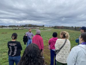 Students atop Horsebarn Hill discuss the ecological impacts of climate change felt around Storrs with Aaron Rosman ’16 (CLAS) ’21 MBA on October 20, 2023.