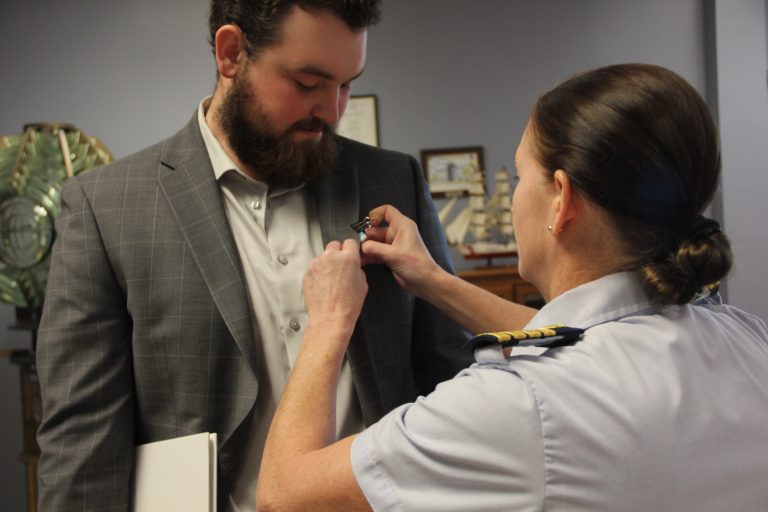 Coast Guard Sector Long Island Sound Commander Captain Elisa M. Garrity pins a medal to John Genther’s lapel in honor of his heroic act on Nov. 6.