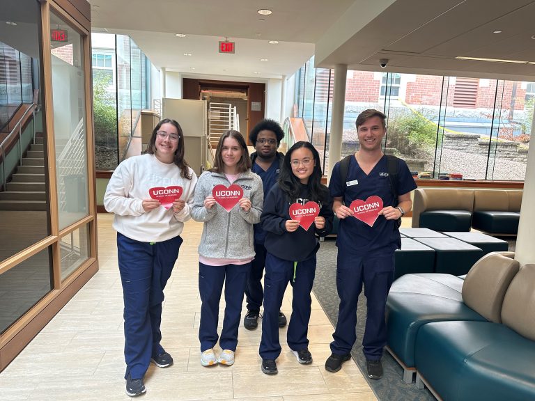 A group of UConn Nursing students hold up red paper hearts for Heart Health Awareness Month.