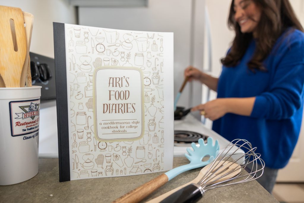 A copy of Arianna Melendez's cookbook, "Ari's Food Diaries," sits in her kitchen at Hilltop Apartments while she cooks