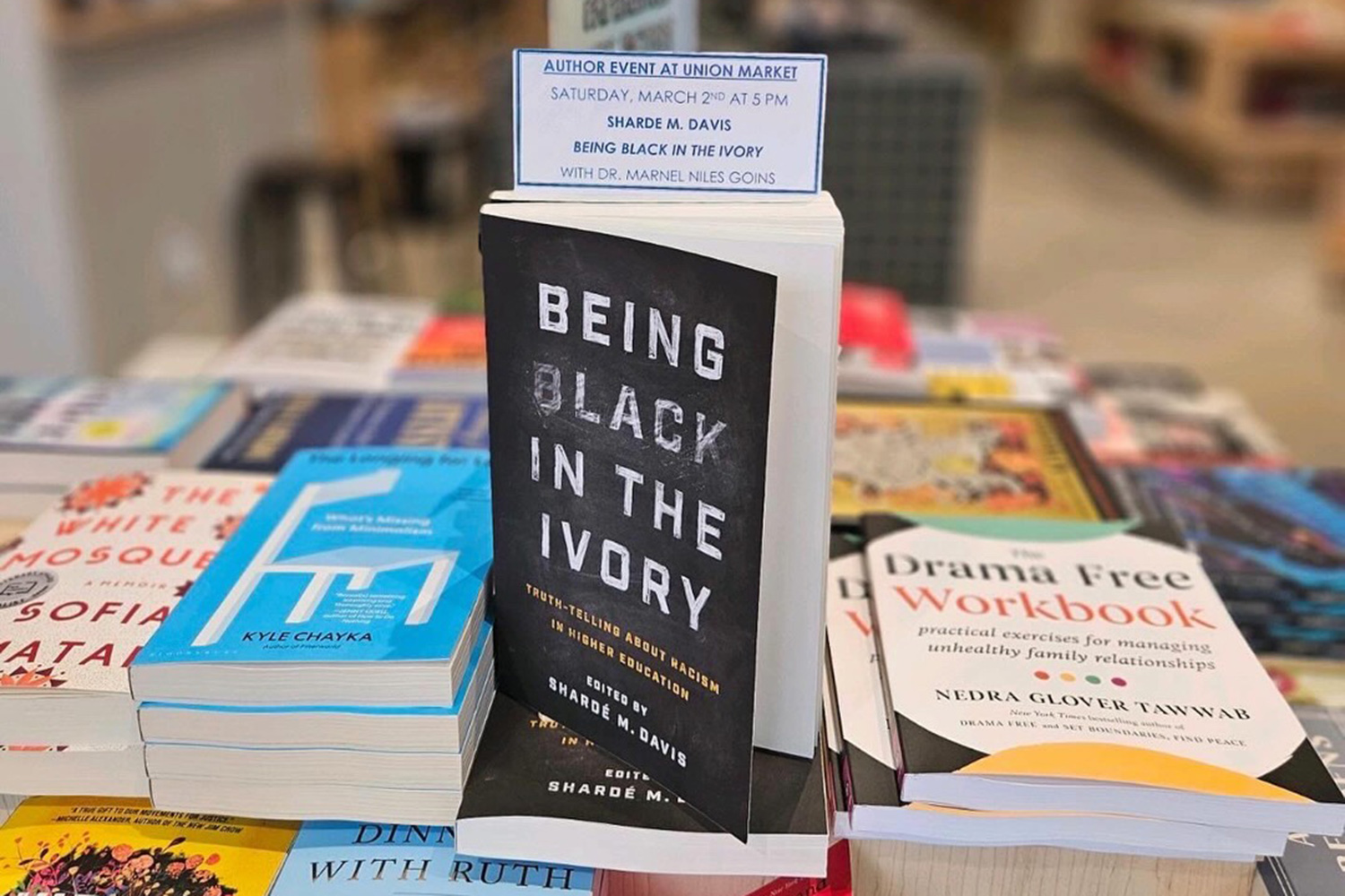 "Being Black in the Ivory" book sitting on a shelf with other books.