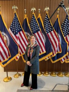 Natalia V. Smirnova, an associate professor-in-residence in the Department of Economics, standing in front of flags inside the U.S. Federal Reserve