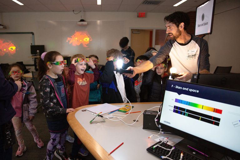 Jonathan Trump uses a light during an activity with young students.