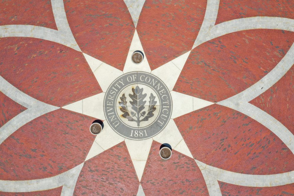 The University of Connecticut oak leaf seal in the center of a brick rosette design.