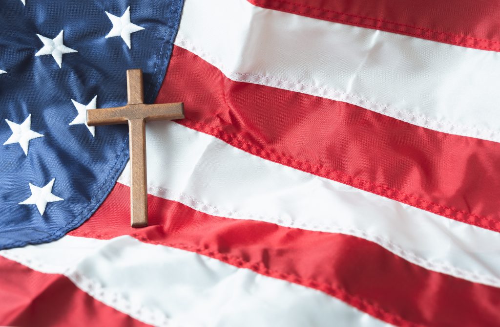 A wooden cross sits on top of an American flag.