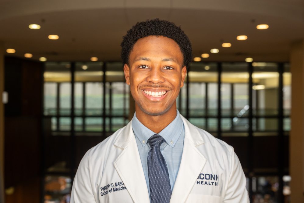 Timothy Mason '24 poses for a photo in the academic wing of the UConn Health complex in Farmington