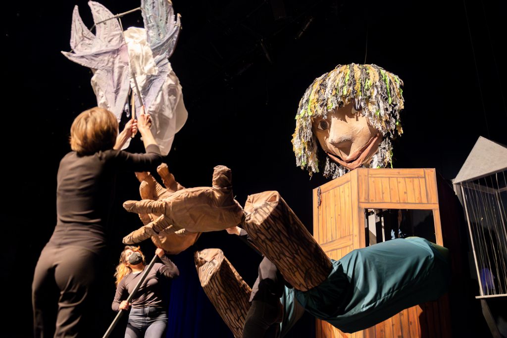 Harry the Giant, the 15-foot-tall puppet featured in “Taurus,” interacts with Blue, one of the rod puppets featured in the show, during tech week rehearsals in the Nafe Katter Theater on Saturday, April 6, 2024. Many of the characters in the show, created by puppet arts student Joanie Papillon, are portrayed through various forms of puppetry.