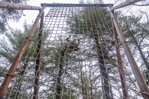 UConn Army ROTC cadet Mary Eddy climbs up the net in one of the obstacle courses at Fort Devens.