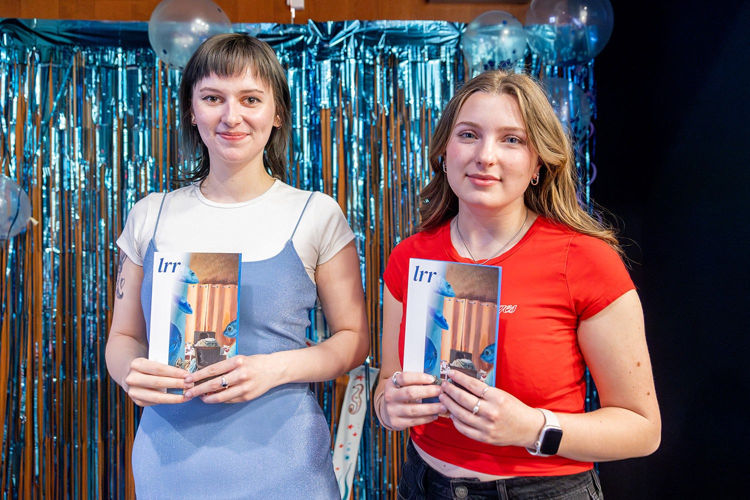 Two students pose holding copies of a literary magazine.