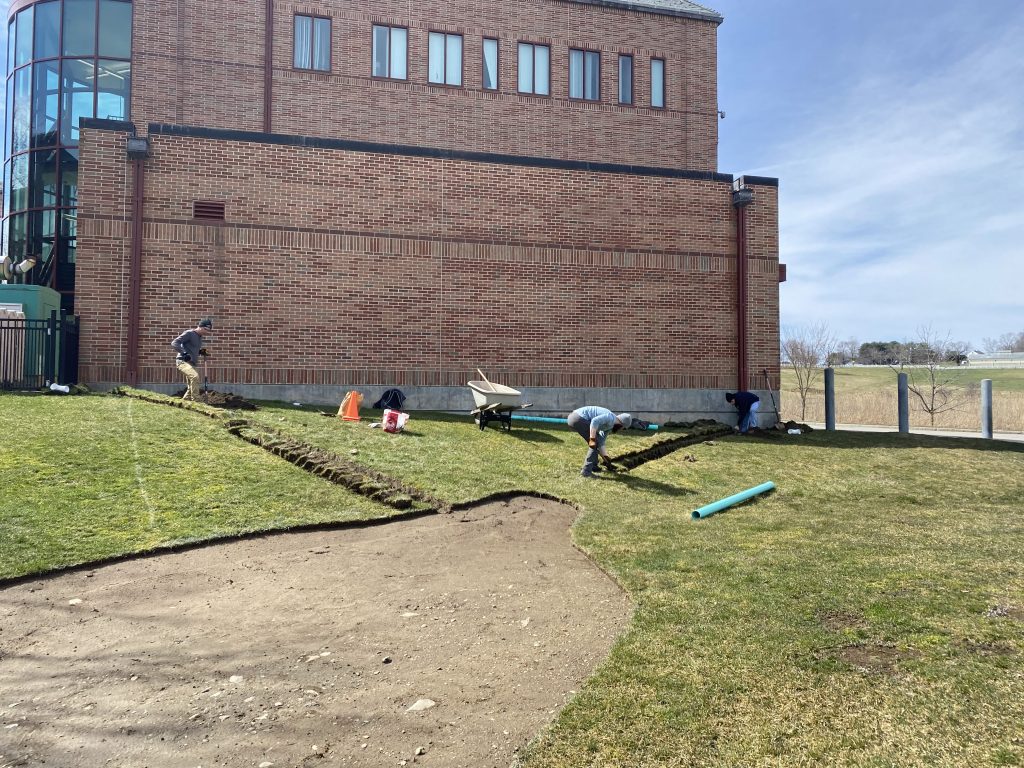 The students worked with Facilities and Dietz to disconnect the downspouts from the adjacent building, dig trenches, and install new piping. 