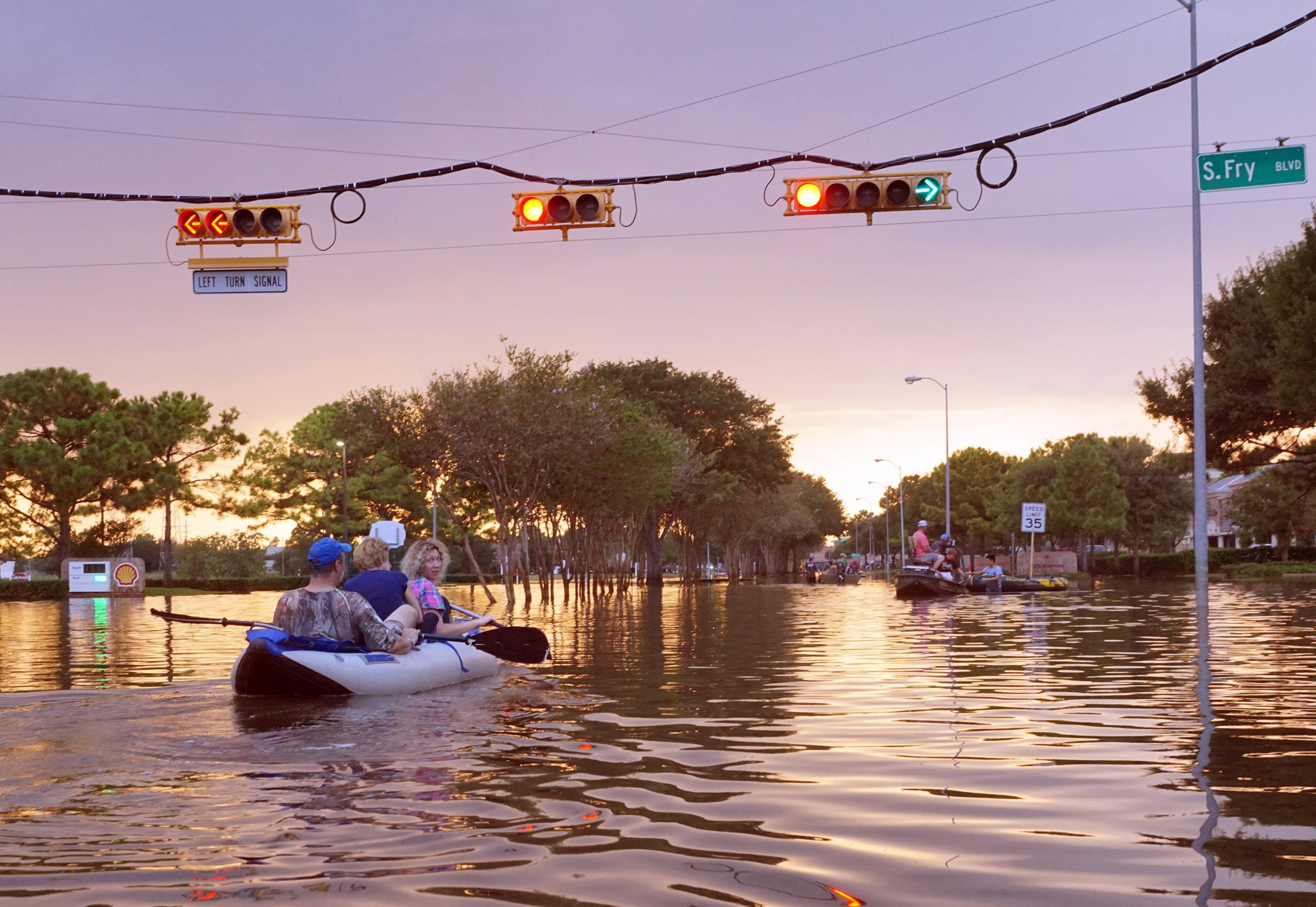 People paddle in a canoe down a flooded street.
