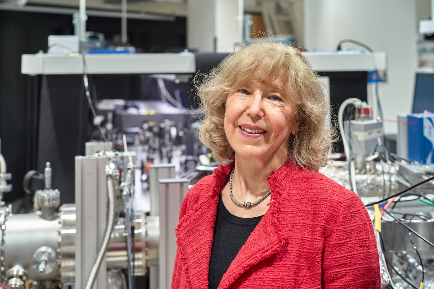 Norah Berrah, professor of physics, standing in front of science equipment in her lab.