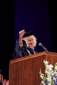 President Radenka Maric lifts an arm in celebration during a commencement ceremony.
