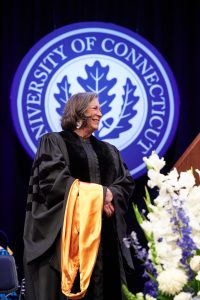 Lynn Malerba stands on stage while receiving her honorary degree.