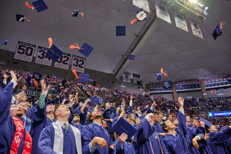 Graduates toss their caps into the air.