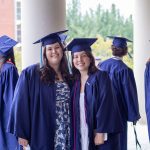 Two female graduates look at the camera and smile