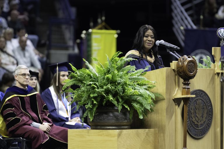 At the podium, Medina Jett '08 EMBA speaks to graduating School of Business students during Commencement 2024. (Nathan Oldham / UConn School of Business)