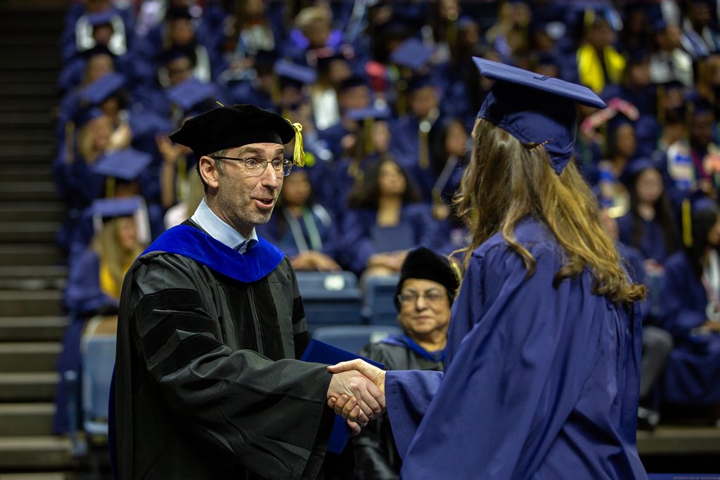 Ofer Harel shakes graduate's hand during commencement ceremony.