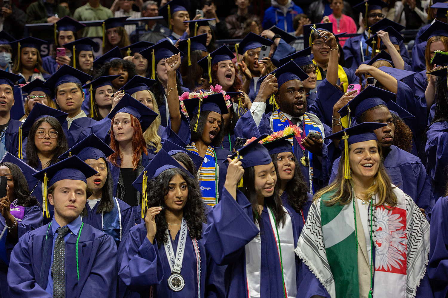 Students celebrate while turning their tassels during commencement ceremony.