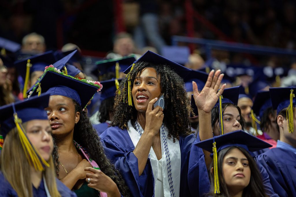 Student waves to crowd during commencement ceremony.