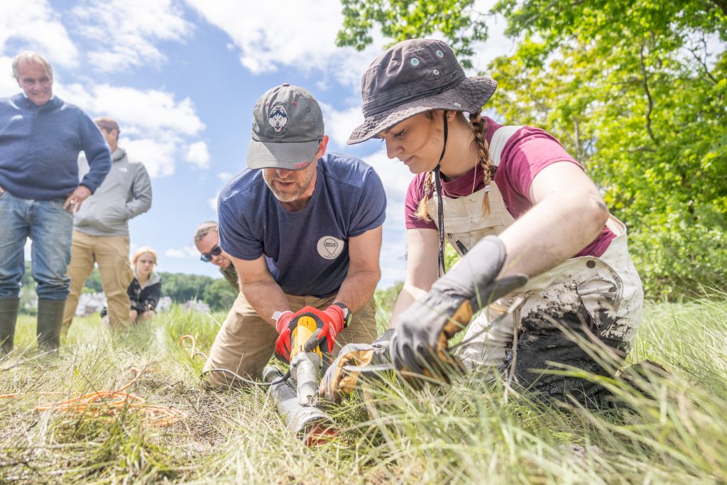 William Ouimet, associate professor of geography at UConn, and Cassie Aimetti '25 (CLAS) work to cut the pipe of the soil cores their team collected.