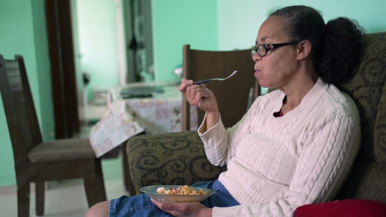 An older woman eats a meager meal alone.