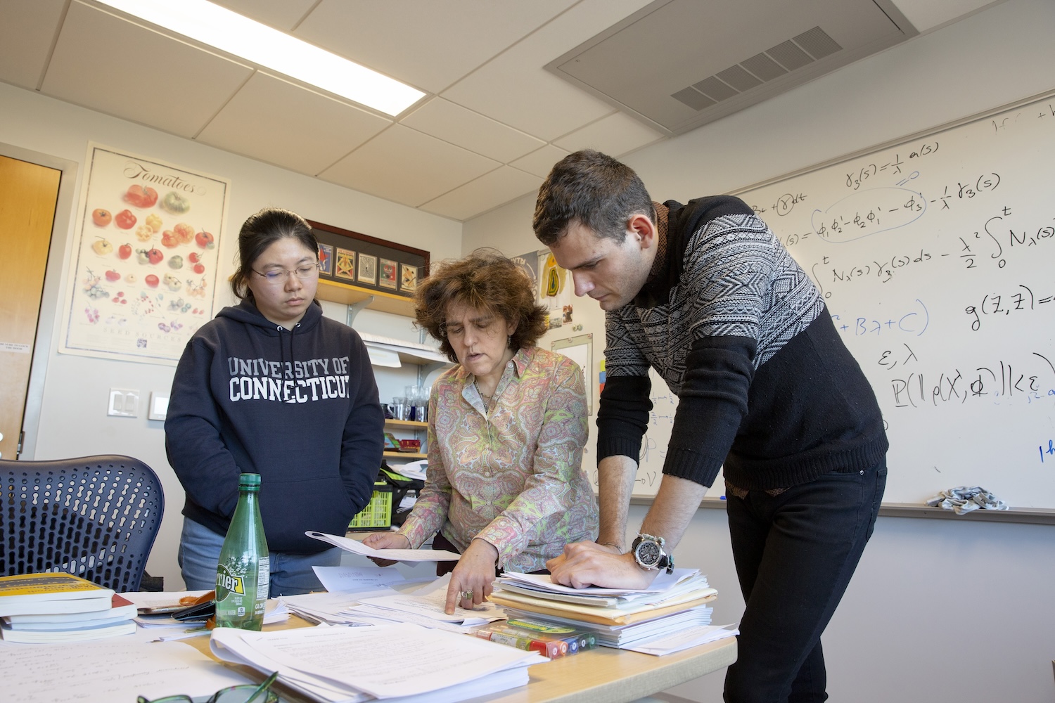 Professor of Mathematics Maria Gordina and two graduate students look over papers set on a table
