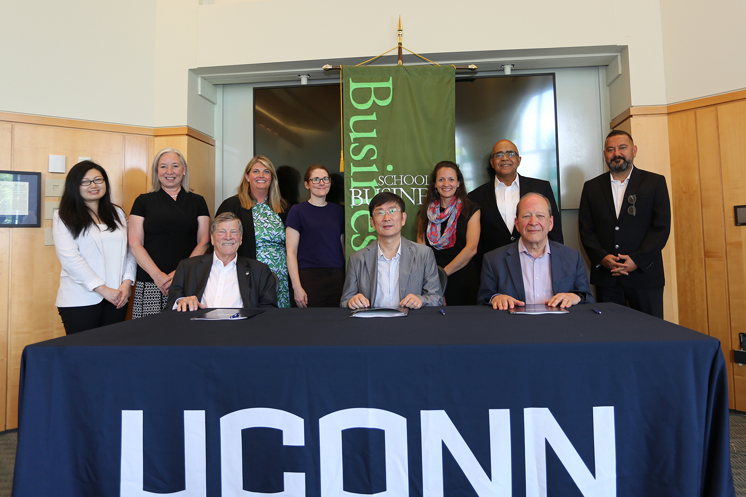 In front, L to R, John A. Elliott, Shenghao Han, and Kent Holsinger, sit for a picture surrounded by key staff that helped create the partnership.