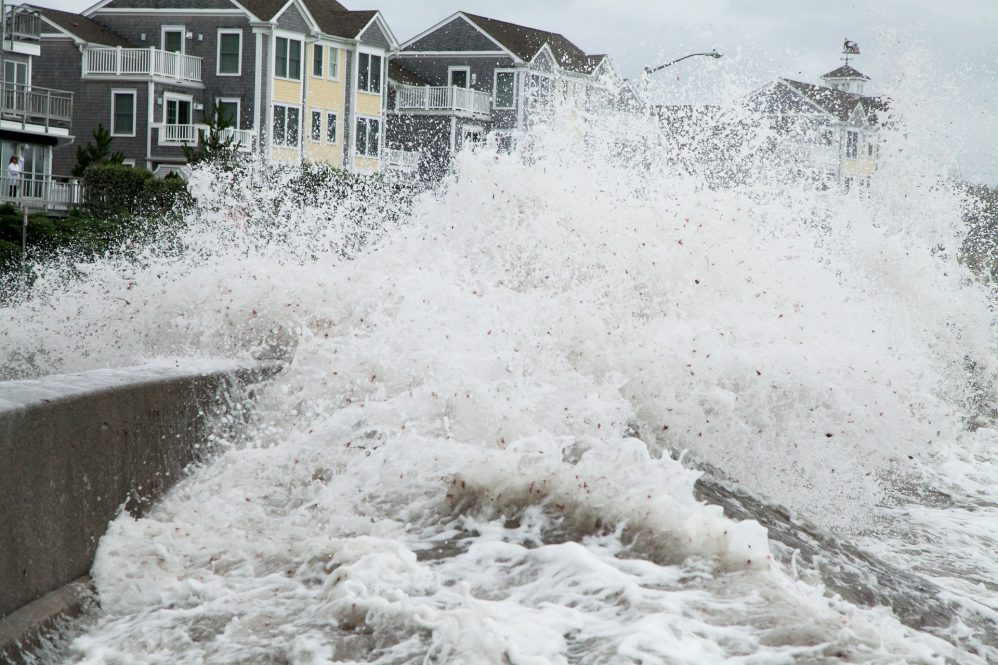 Waves crashing against a sea wall and houses