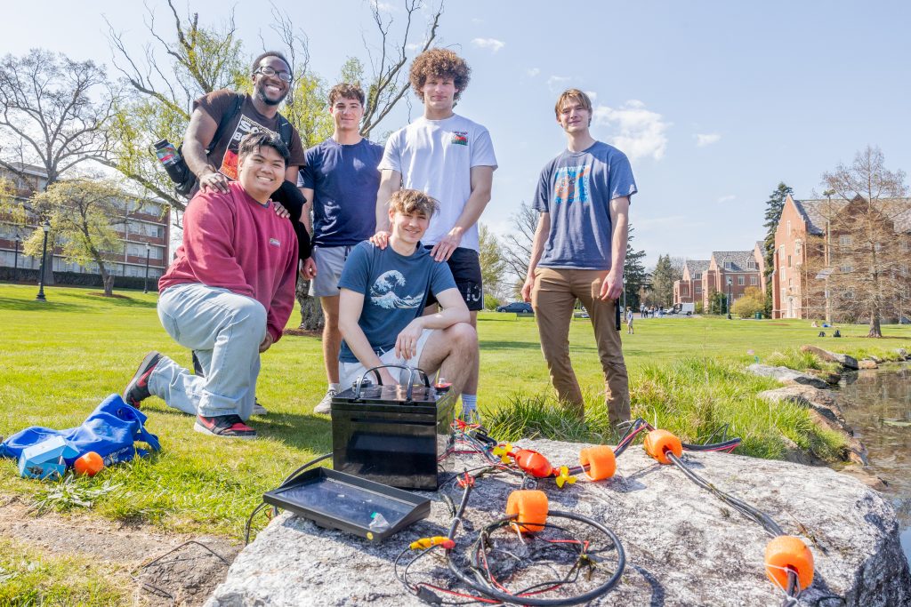 Underwater Robotics Club members (front row, from left) Marc Lopez '25, Joey St. Hilaire '25, (back row, from left) Joshua Okoli '25, Colin Sheardwright '27, Simon Koepfer '25 and Oliver Mackinnon '25 pose for a photo by Mirror Lake with the small underwater robot prototype they built