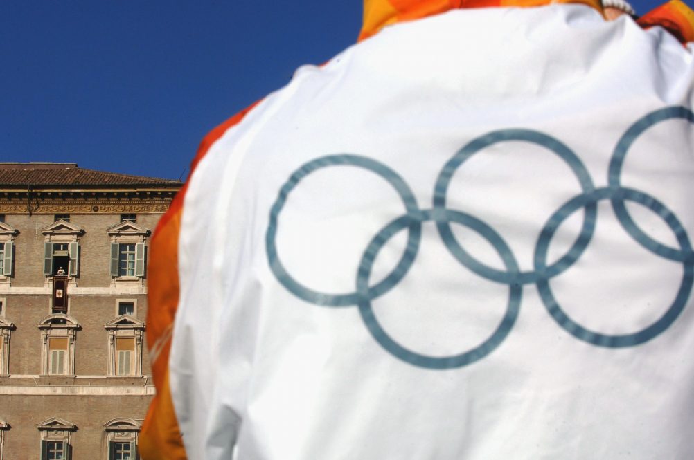 The pope looks down on St. Peter's Square with an Olympic athlete in the foreground.