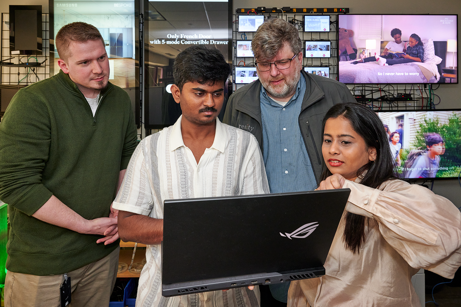 Students and a faculty member gather in front of a laptop.