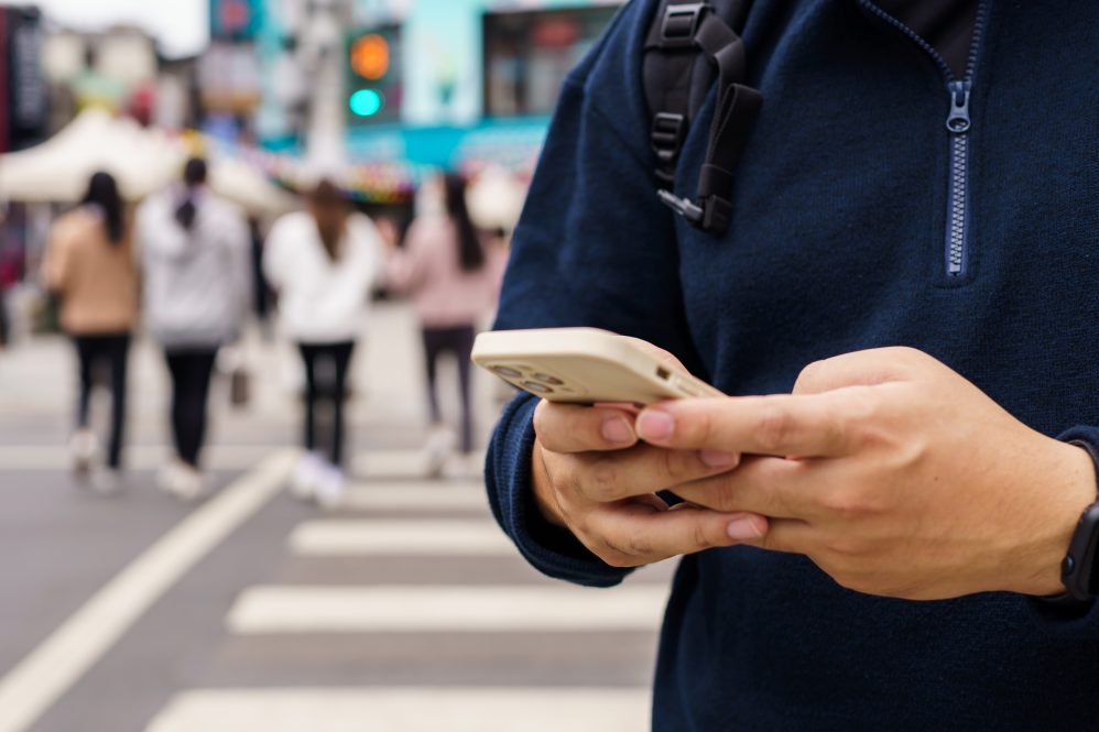 Man in a navy half-zip sweater using a smartphone