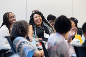 A laughing woman surrounded by other participants of a summer institute