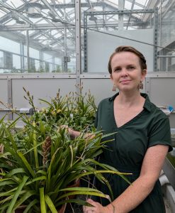 Karolina Heyduk poses next to some plants in her lab.