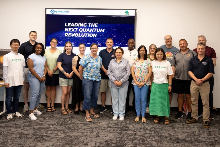 Five UConn faculty members and 12 local K-12 educators stand in front of a screen that reads 