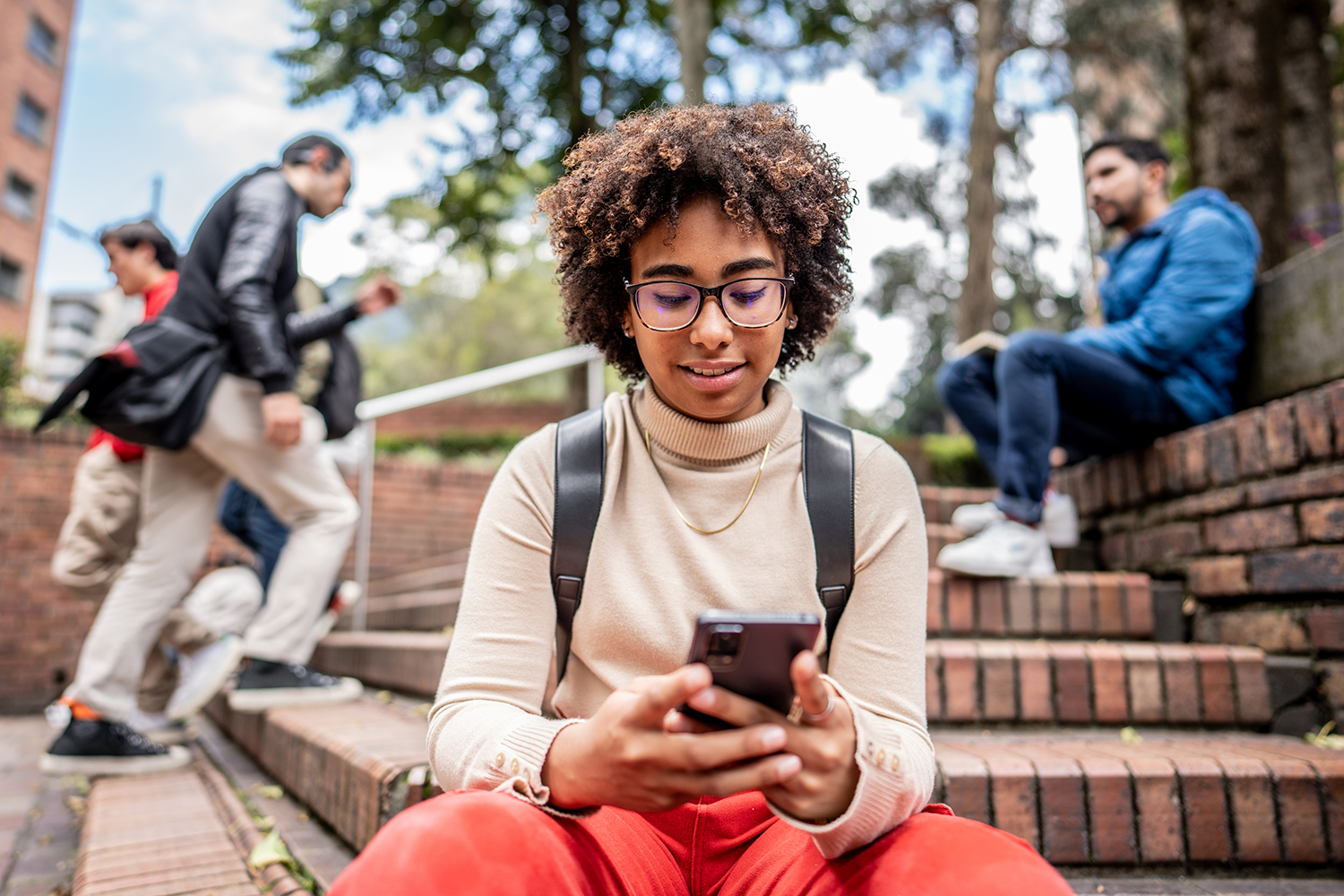 Young student using mobile phone on stairs outdoors