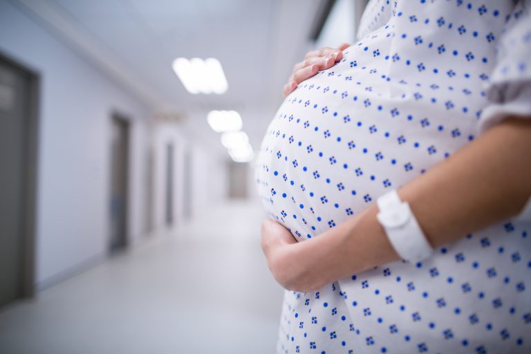 A pregnant woman in the hallway of a hospital.