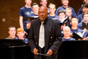 Peter Bagley standing in front of a choir he's directing